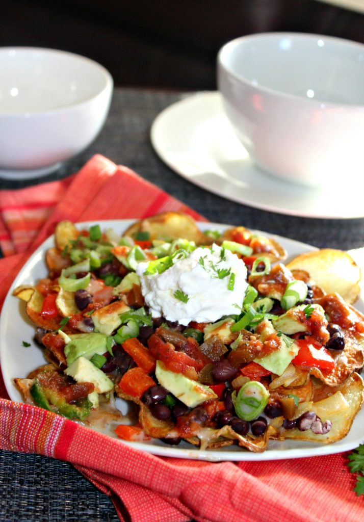 veggie potato nachos on a  white plate with salsa and sour cream