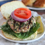 Spinach and feta turkey burger on a roll topped with onions and tomatoes