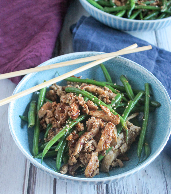 spicy green beans and pork stir fry in a bowl with chop sticks
