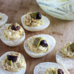 Deviled eggs on a board with olives