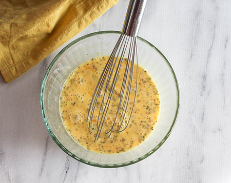 eggs scrambled in bowl with whisk