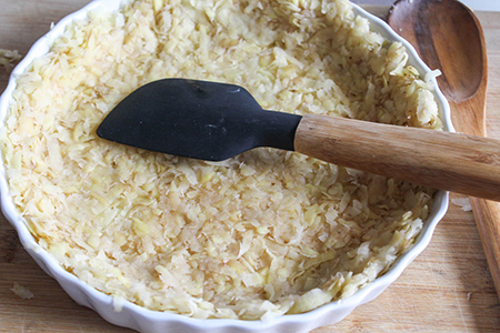 Process step 4: shredded potatoes pressed into a pie pan with a spatula, 