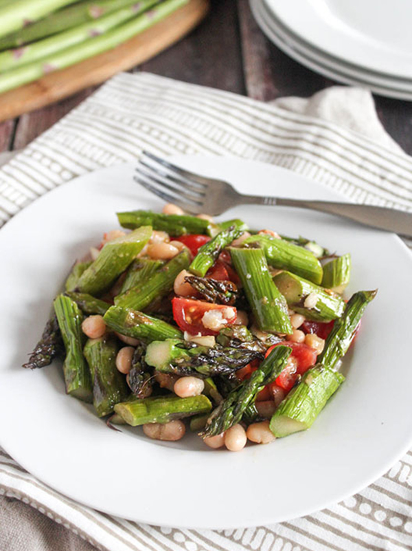 Asparagus salad in a white bowl with a fork