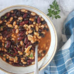 an overhead veiw of slow cooked beans in a bowl with a spoon