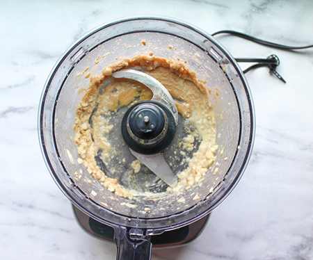 A view of garlic, tahini and lemon juice blended into a paste