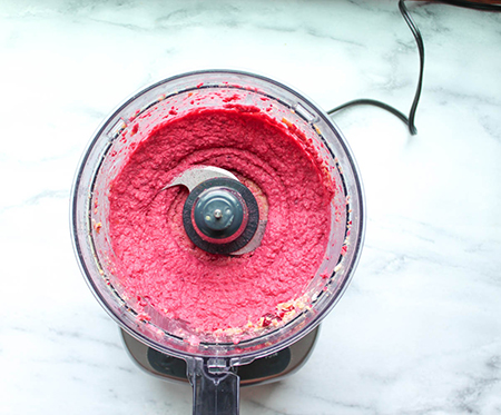 Roasted beet humus fully processed in a food processor bowl