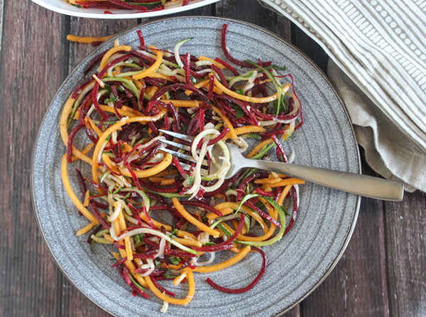 A plate full of veggie noodles wrapped around a fork