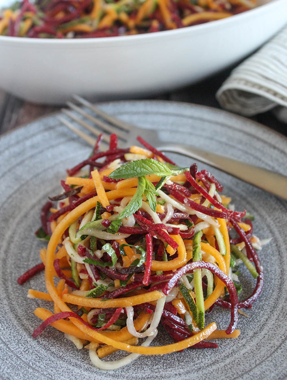 spiralized vegetables on a plate topped with fresh mint