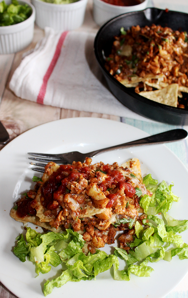 Vegetarian nachos finished recipe on white plate and shredded Romaine lettuce with a fork on side.