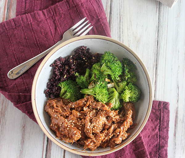 Slow cooked Asian Pork in a bowl with broccoli and rice with fork