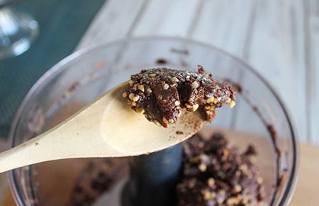 Spoon displaying ingredients to show the dough-like texture of the brownie.