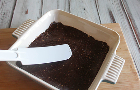 a spatula spreading the brownie dough into a pan