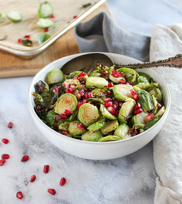 Brussels sprouts in a white bowl with a serving spoon