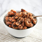 a close up look at a bowl of roasted cashews glazed with maple syrup