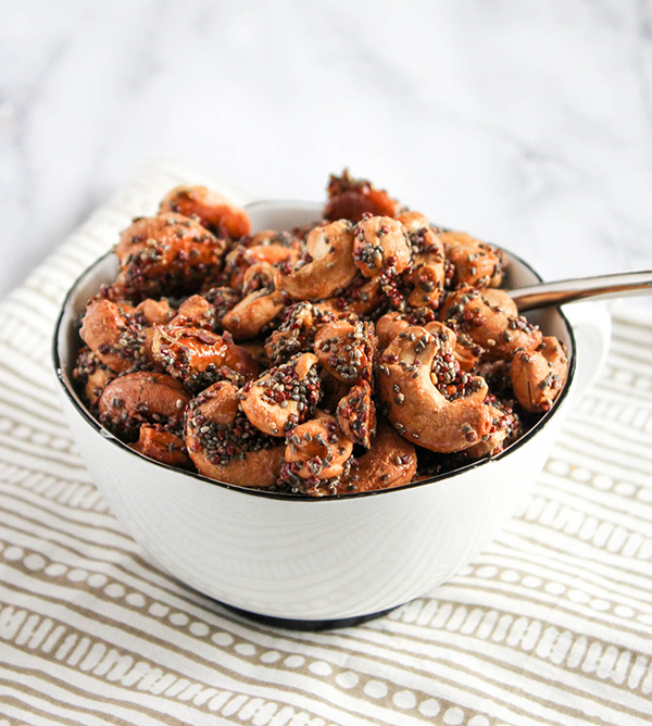 a close up look at a bowl of roasted cashews glazed with maple syrup