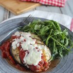 Eggplant Parmesan casserole on a blue plate with arugula