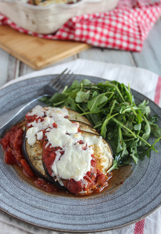 Eggplant Parmesan casserole on a blue plate with arugula