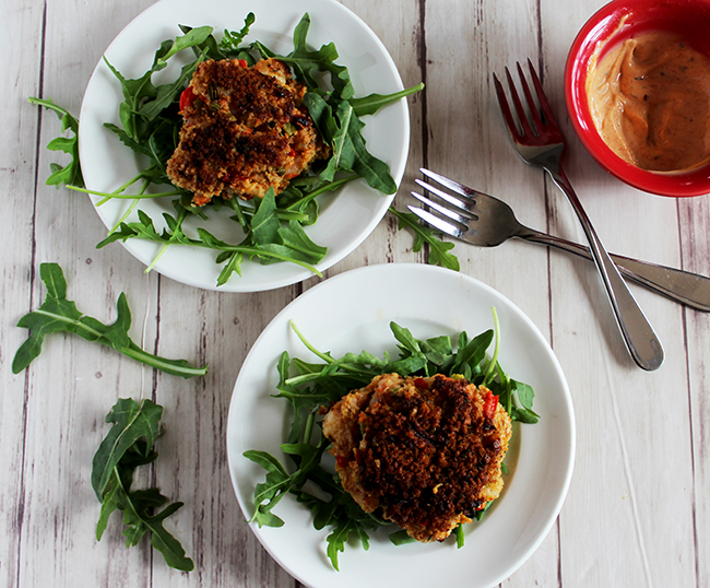 overhead view of two shimp cakes on white plates on top of arugula