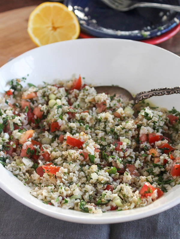 cauliflower tabbouleh in a white bowl with a spoon