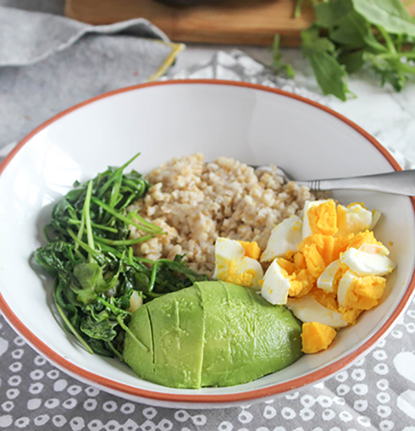 savory breakfast bowl filled with avocado, sauteed greens, whole grains and a hard boiled egg.