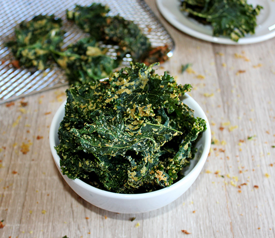 Air Fryer kale chips in a white bowl with a tray in the background