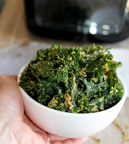 Air fryer kale chips in a white bowl in a hand