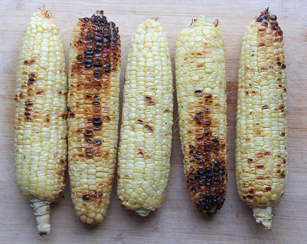 charred grilled corn on a cutting board