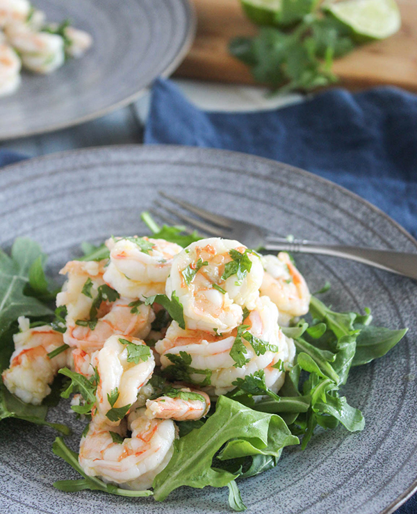 cilantro lime shrimp on top of baby arugula on a plate