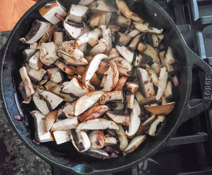 mushrooms cooking with onions in a skillet