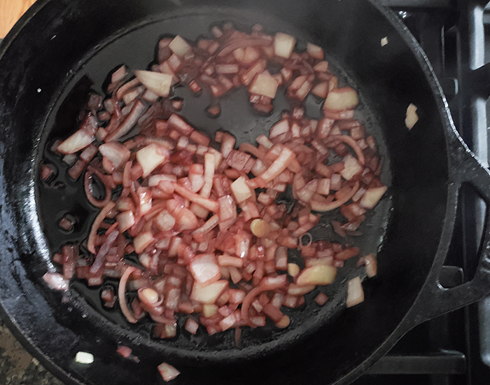 Overhead shot of onions cooking in a skillet with wine