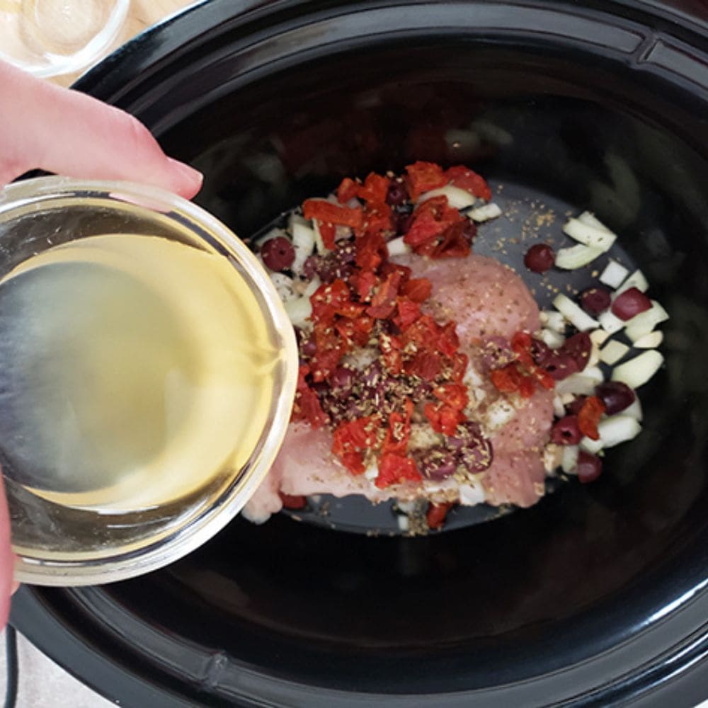 all of the ingredients in a slow cooker with the broth pouring in