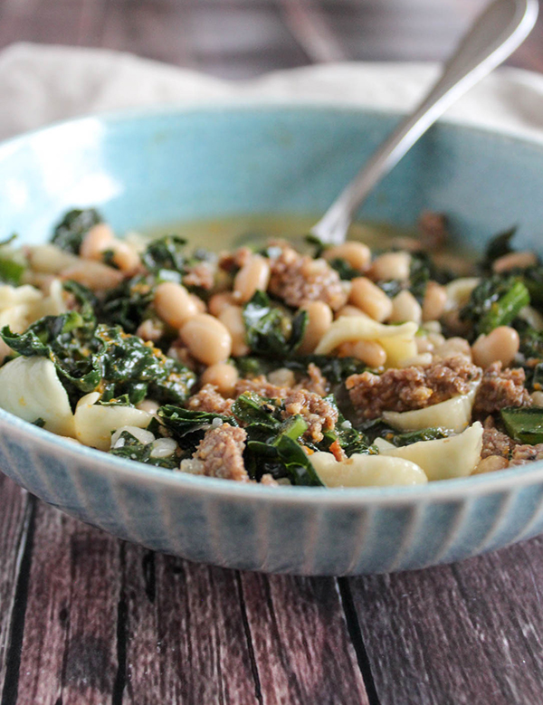 a close up picture of sausage and kale soup in a bowl