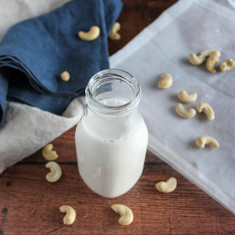 homemade cashew milk in a milk bottle with cashews on a table