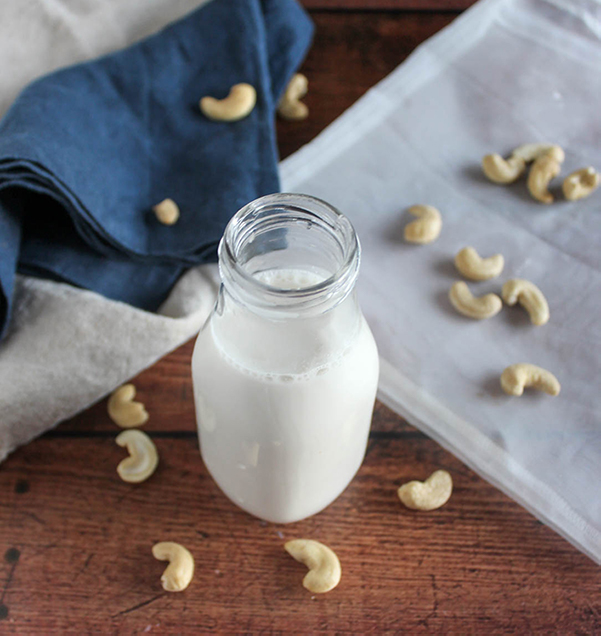 homemade cashew milk in a milk bottle with cashews on a table