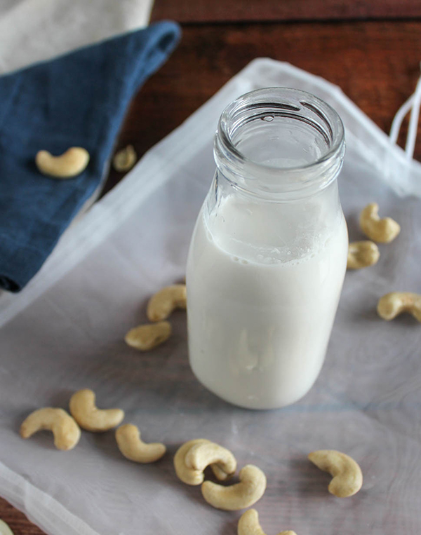 homemade cashew milk in a milk bottle with cashews in the background