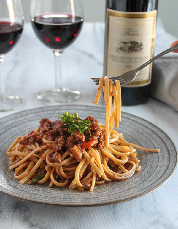 Spaghetti with bologonese sauce on a plate picked up with a fork