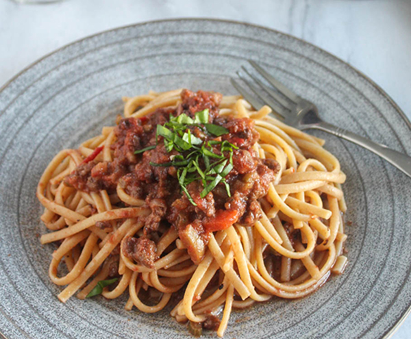 spaghetti covered with bolognese sauce and basil ribbons on top