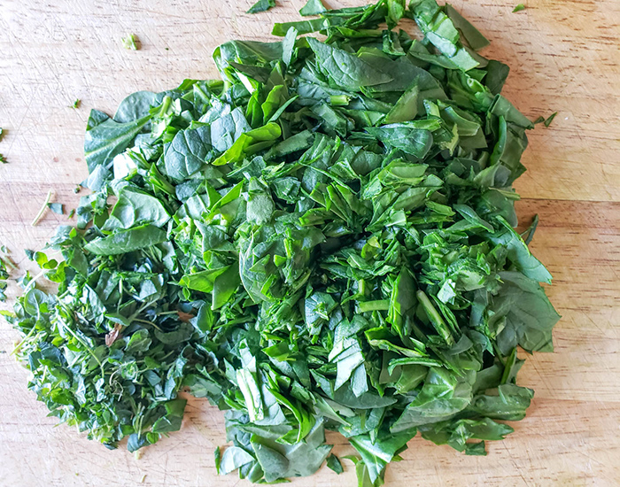 an overhead view of chopped spinach and oregano