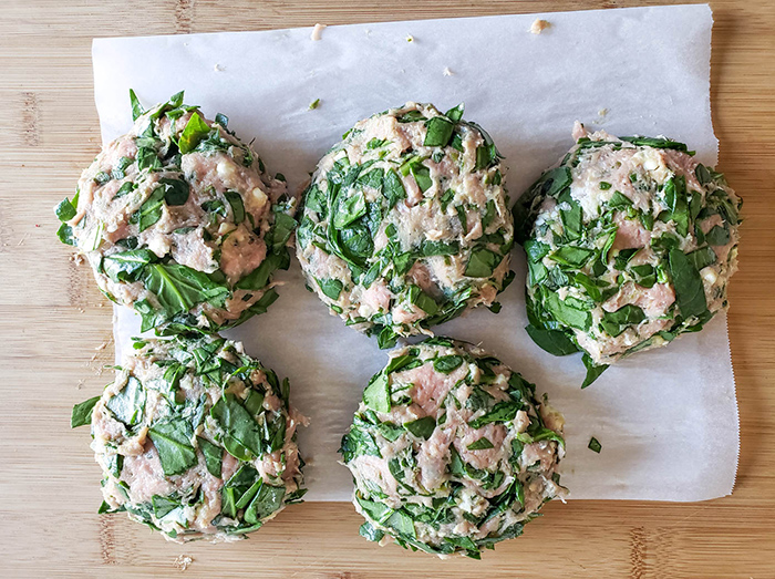 uncooked spinach burgers on a board