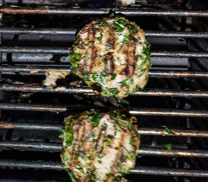 two burgers cooking on the grill