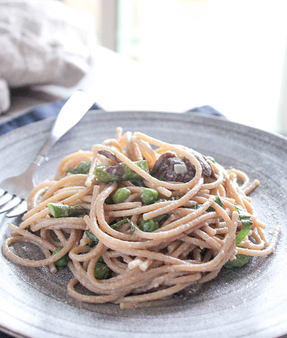 a close up view of creamy pasta with spring vegetables
