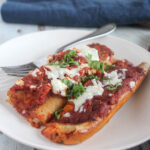 manicotti on a plate with cheese and basil on top