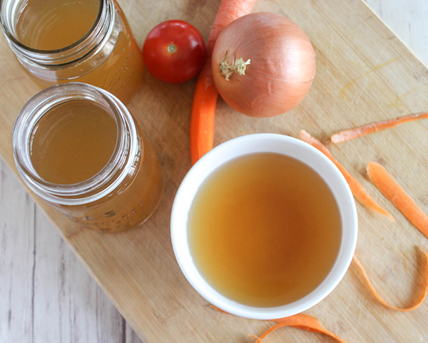 Overhead view of broth in a bowl and mason jars