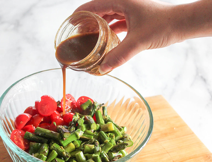 salad ingredients ina bowl with dressing pouring in