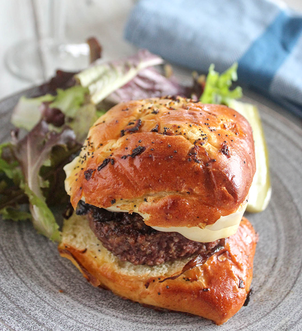 caramelized onion burger on a plate with a salad