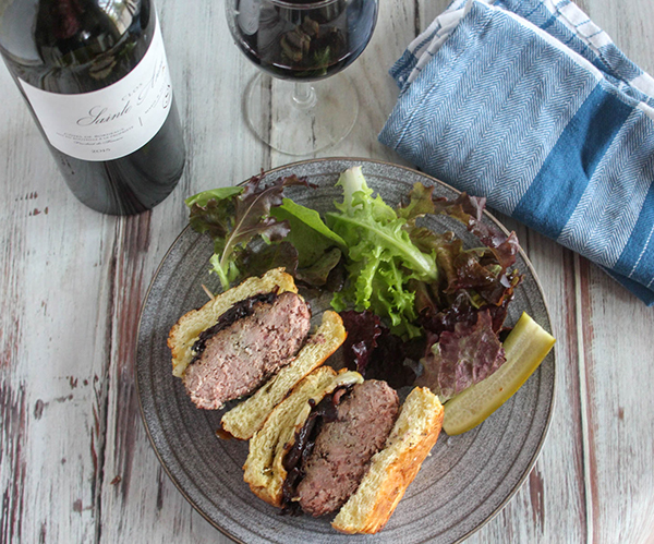 caramelized onion burger cut in half on a plate with a salad