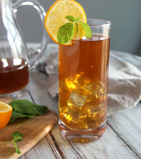 Iced tea in a glass with a pitcher in the background