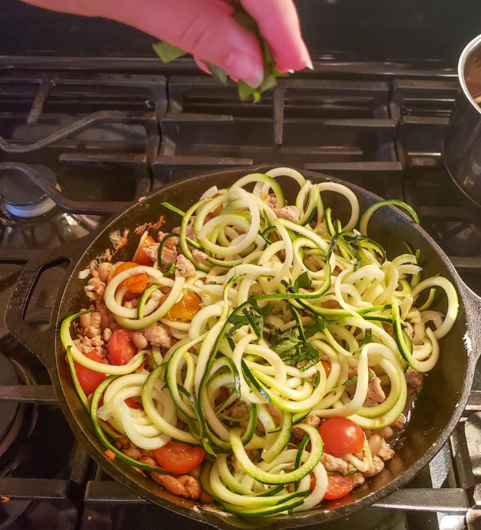 zucchini noodles with herbs being sprinkled on