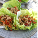 Three Asian chicken lettuce wraps on a plate