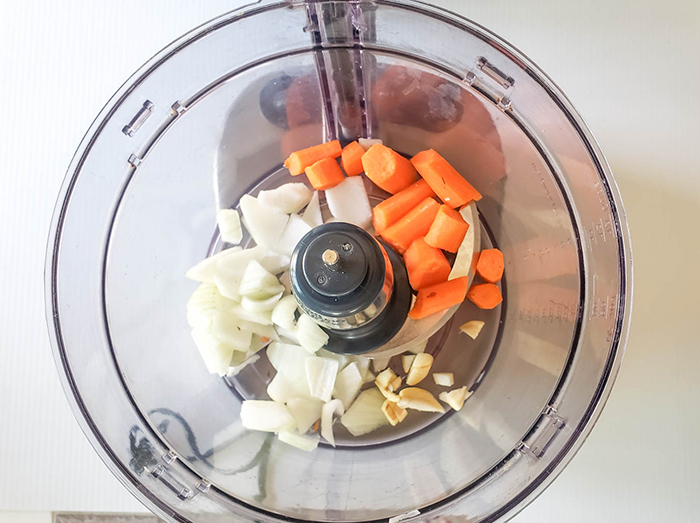 first step of making veggie burgers onions and carrots in a food processor 